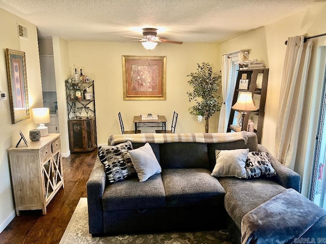 living room featuring ceiling fan, dark hardwood / wood-style floors, and a textured ceiling