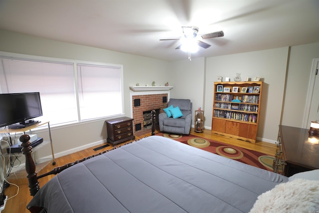 bedroom with hardwood / wood-style floors, a fireplace, and ceiling fan