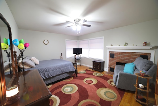 bedroom featuring a fireplace, wood-type flooring, and ceiling fan