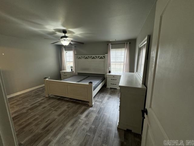 bedroom featuring dark hardwood / wood-style flooring, multiple windows, and ceiling fan