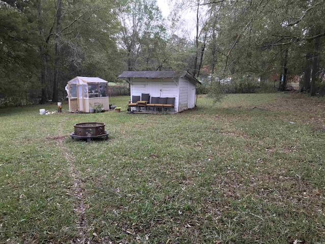 view of yard featuring a fire pit and an outdoor structure