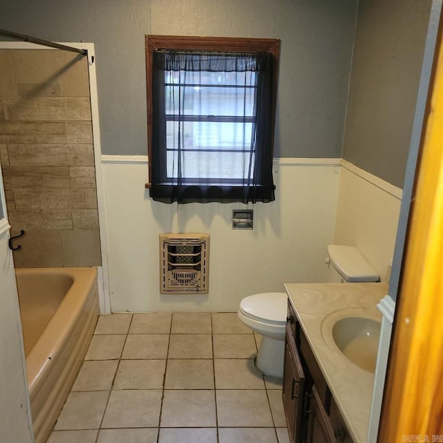 bathroom featuring tile patterned flooring, a tub to relax in, heating unit, toilet, and vanity