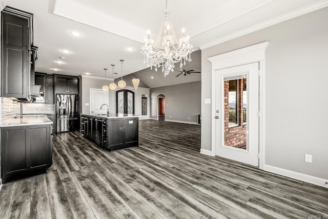 kitchen featuring dark hardwood / wood-style flooring, decorative light fixtures, an island with sink, and stainless steel fridge