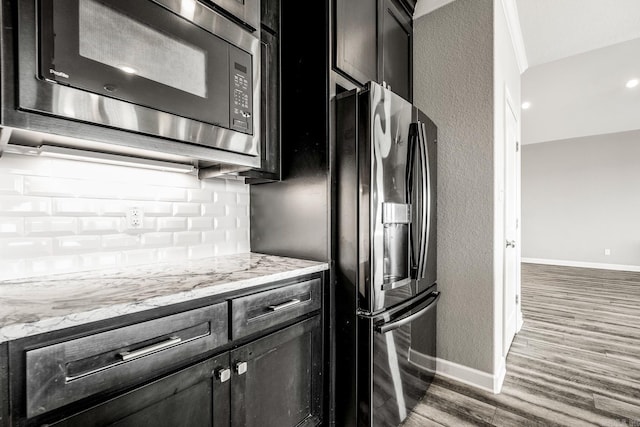 kitchen with light stone counters, appliances with stainless steel finishes, and hardwood / wood-style flooring