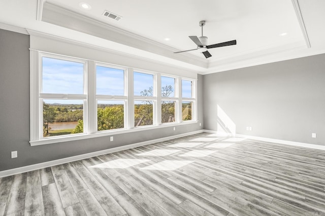 unfurnished room with light hardwood / wood-style floors, ceiling fan, a raised ceiling, and ornamental molding