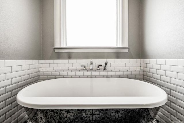 bathroom featuring tile walls, a bath, and sink