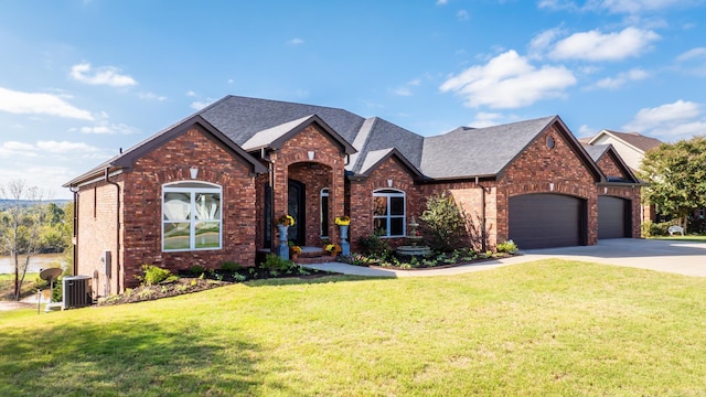 view of front of house featuring a garage, cooling unit, and a front lawn