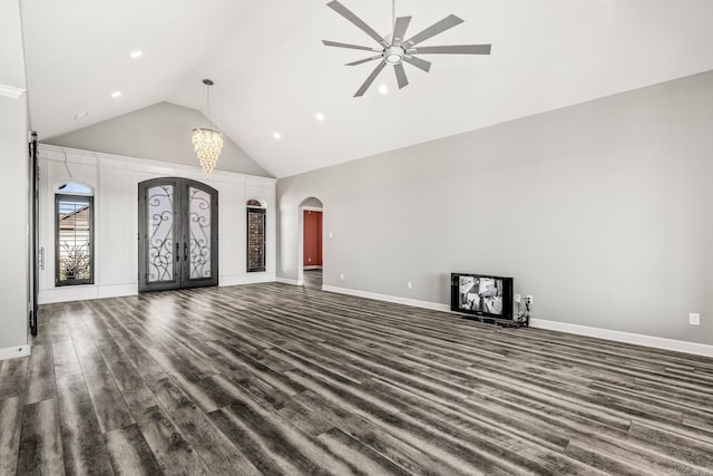 unfurnished living room with dark hardwood / wood-style flooring, high vaulted ceiling, french doors, and ceiling fan with notable chandelier