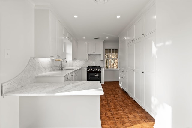 kitchen with white cabinets, kitchen peninsula, high end stainless steel range oven, and sink