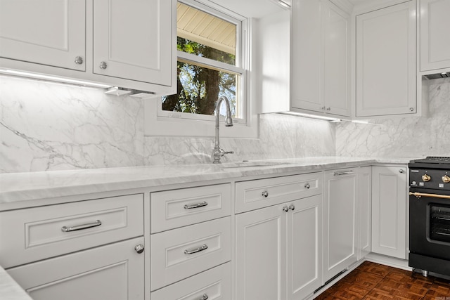 kitchen featuring light stone countertops, dark parquet floors, white cabinets, stove, and decorative backsplash