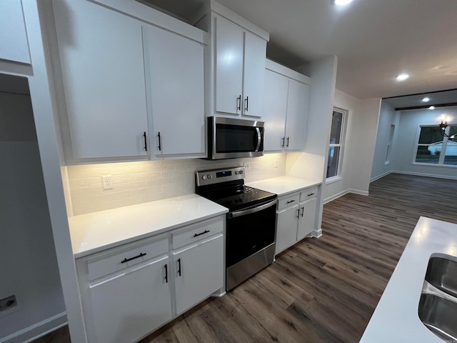 kitchen featuring dark wood-type flooring, white cabinetry, appliances with stainless steel finishes, and tasteful backsplash