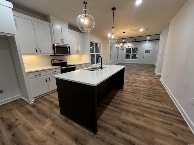 kitchen featuring stainless steel appliances, white cabinets, sink, an island with sink, and decorative light fixtures