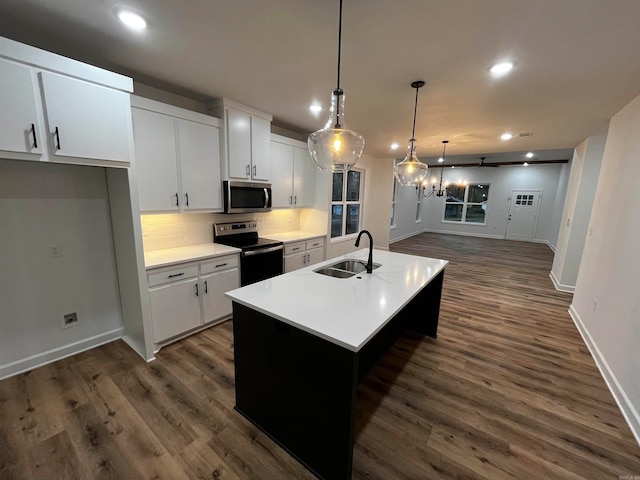 kitchen with white cabinetry, appliances with stainless steel finishes, decorative light fixtures, and a center island with sink