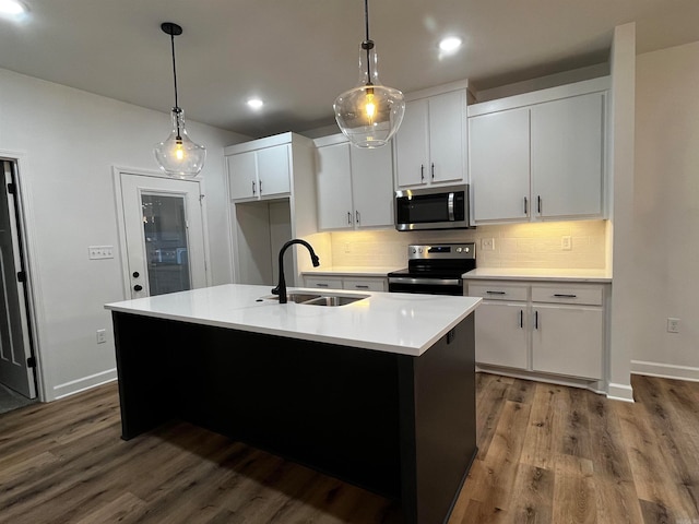 kitchen with white cabinetry, appliances with stainless steel finishes, decorative light fixtures, sink, and a kitchen island with sink