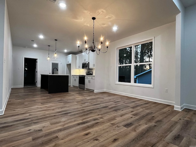 kitchen featuring white cabinetry, appliances with stainless steel finishes, hanging light fixtures, and a center island with sink