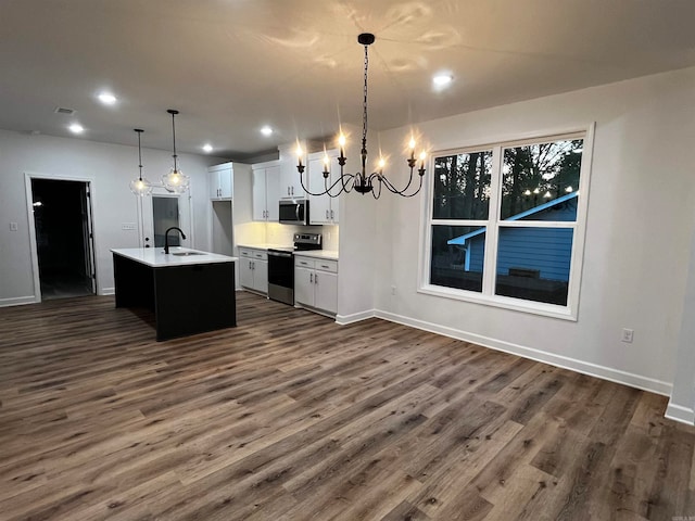 kitchen with white cabinets, a kitchen island with sink, dark hardwood / wood-style floors, pendant lighting, and appliances with stainless steel finishes