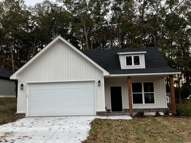2497 Janet, Benton, AR 72015 - view of front of home featuring concrete driveway, a garage, a shingled roof, and board and batten siding