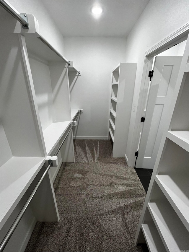 walk in closet featuring dark colored carpet