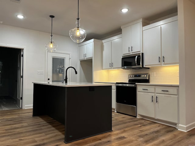 kitchen with stainless steel appliances, dark hardwood / wood-style floors, white cabinetry, and a kitchen island with sink