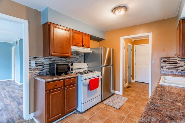 kitchen featuring stainless steel appliances, sink, tasteful backsplash, and light tile patterned floors