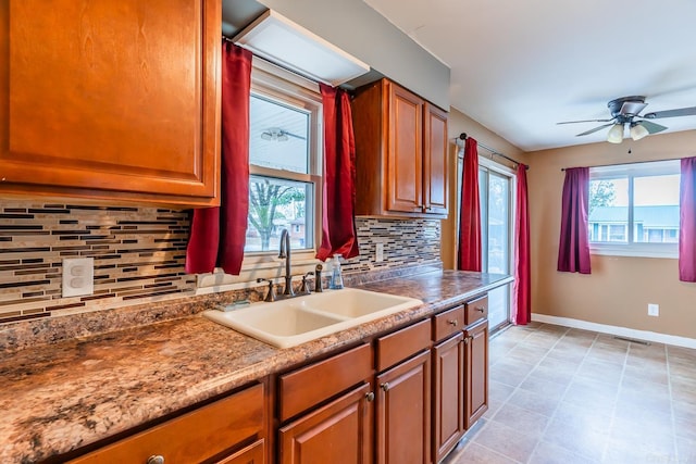 kitchen featuring backsplash, sink, light stone counters, and ceiling fan