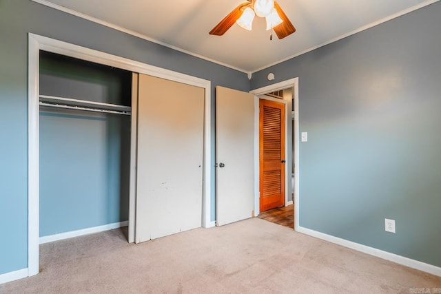 unfurnished bedroom featuring ornamental molding, light colored carpet, ceiling fan, and a closet