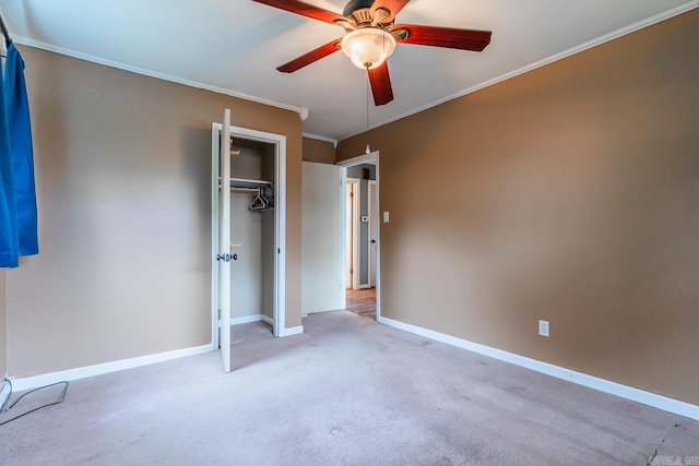 unfurnished bedroom with ceiling fan, a closet, crown molding, and light colored carpet