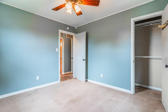 unfurnished bedroom featuring light colored carpet, ceiling fan, a closet, and ornamental molding