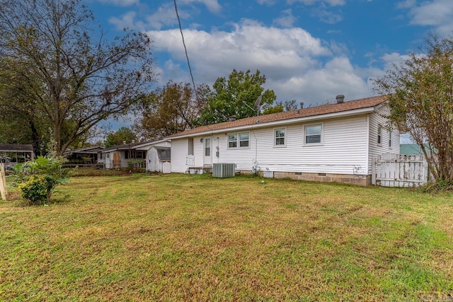 rear view of property with central air condition unit and a lawn