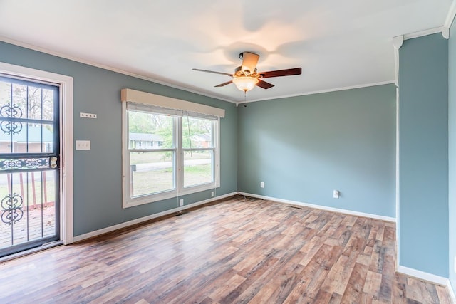 unfurnished room featuring ornamental molding, a wealth of natural light, wood-type flooring, and ceiling fan