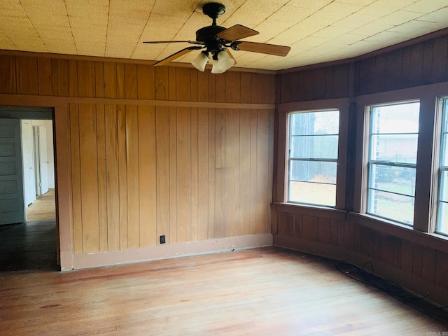 spare room featuring ceiling fan, wooden walls, and light hardwood / wood-style flooring