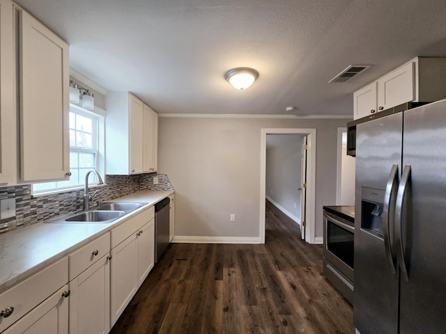 kitchen featuring dark hardwood / wood-style floors, tasteful backsplash, white cabinetry, sink, and stainless steel appliances