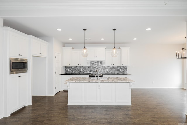 kitchen featuring hanging light fixtures, white cabinets, an island with sink, and dark hardwood / wood-style flooring