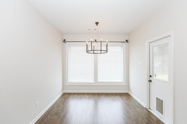 unfurnished dining area with a wealth of natural light, a notable chandelier, and dark hardwood / wood-style floors