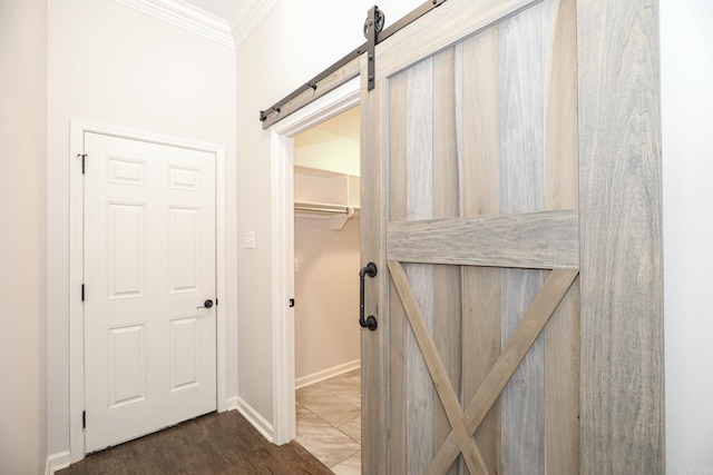 interior space with a barn door, ornamental molding, and dark hardwood / wood-style floors