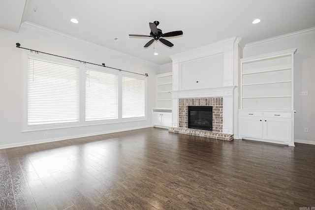 unfurnished living room featuring a brick fireplace, dark hardwood / wood-style flooring, ceiling fan, and crown molding