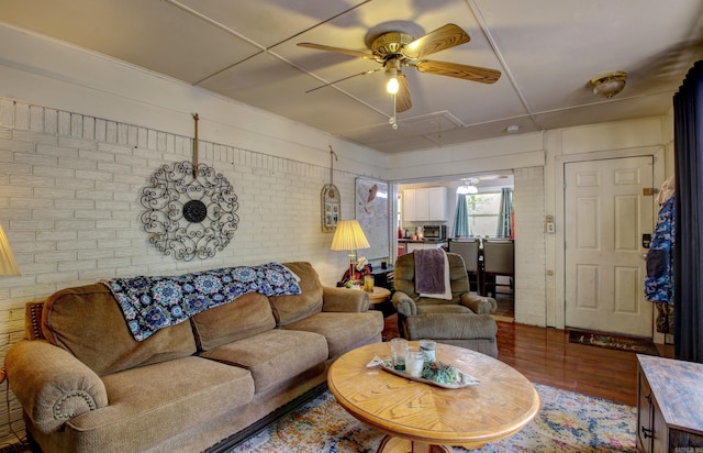 living room with wood-type flooring, brick wall, and ceiling fan