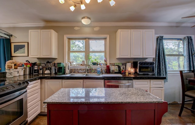 kitchen with dark stone counters, white cabinets, sink, crown molding, and appliances with stainless steel finishes