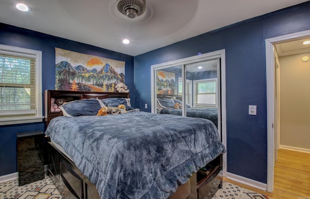 bedroom featuring light wood-type flooring, multiple windows, and ceiling fan