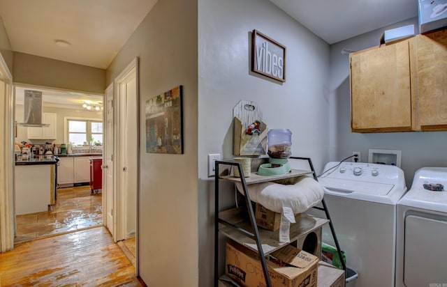 laundry area with light hardwood / wood-style flooring, cabinets, and washing machine and clothes dryer