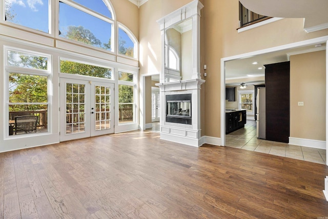 unfurnished living room with a towering ceiling, plenty of natural light, and light wood-type flooring