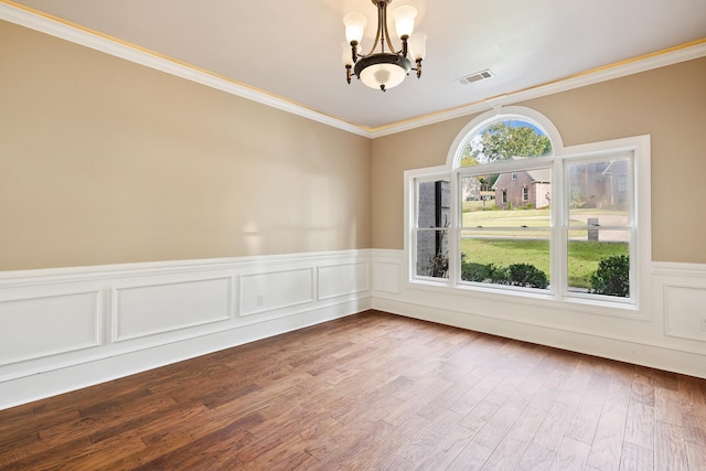 empty room with a chandelier, wood-type flooring, ornamental molding, and plenty of natural light