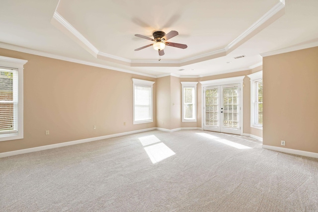 unfurnished room featuring french doors, light carpet, ornamental molding, ceiling fan, and a raised ceiling