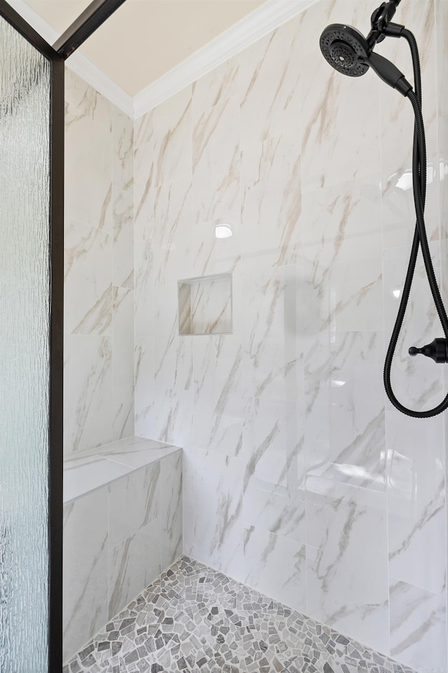 bathroom with crown molding and a tile shower