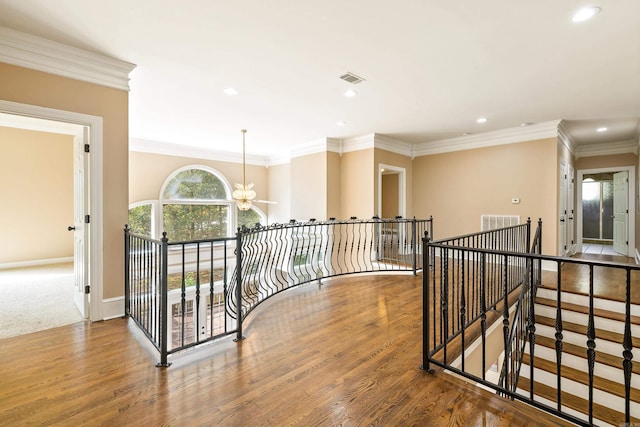 hallway featuring an inviting chandelier, hardwood / wood-style floors, and ornamental molding