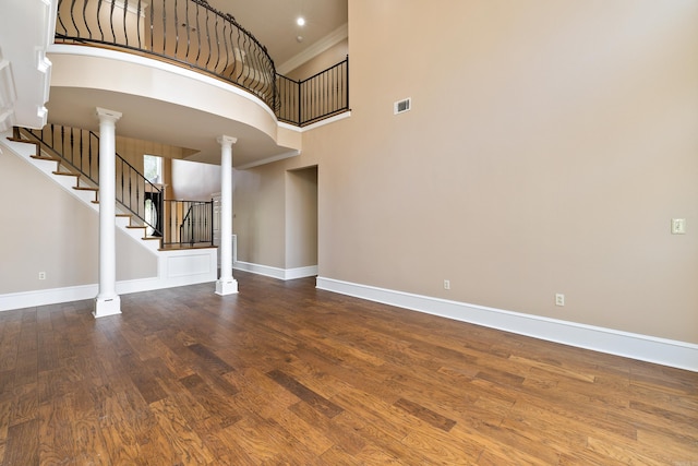 interior space with a high ceiling, ornate columns, and hardwood / wood-style flooring