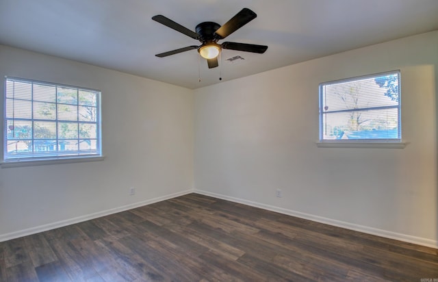 empty room with ceiling fan, plenty of natural light, and dark hardwood / wood-style flooring