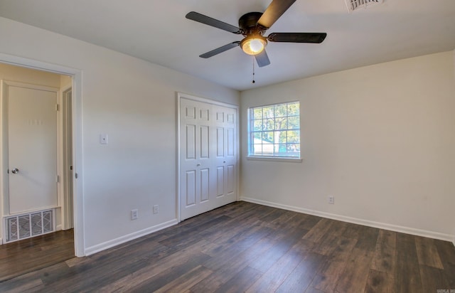 unfurnished bedroom featuring dark wood-type flooring, a closet, and ceiling fan