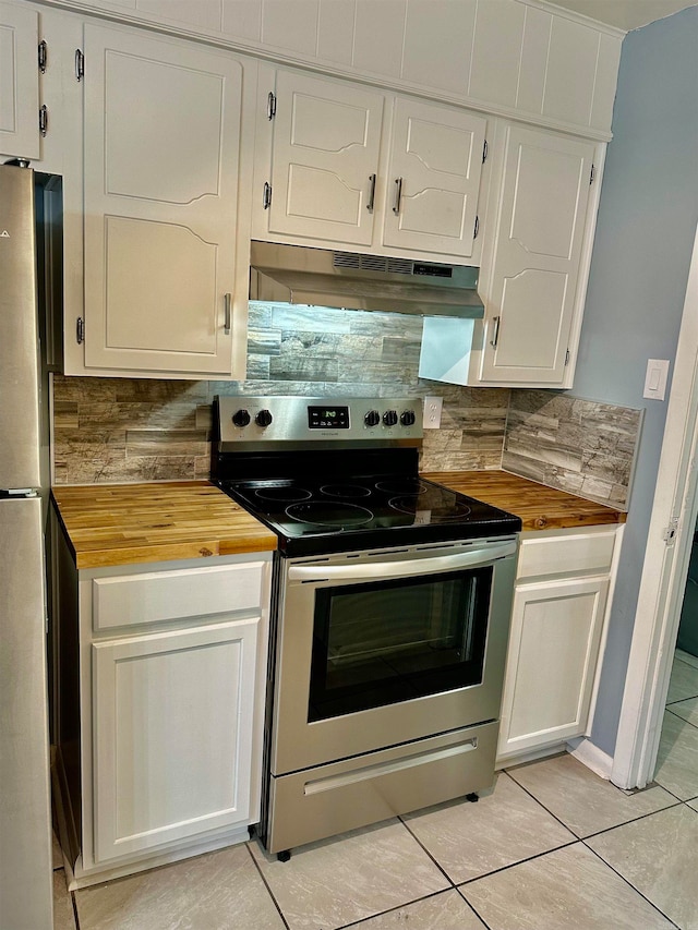 kitchen with white cabinetry, extractor fan, appliances with stainless steel finishes, light tile patterned floors, and butcher block countertops