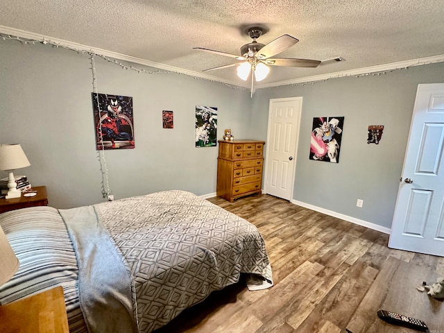 bedroom with ceiling fan, hardwood / wood-style floors, crown molding, and a textured ceiling